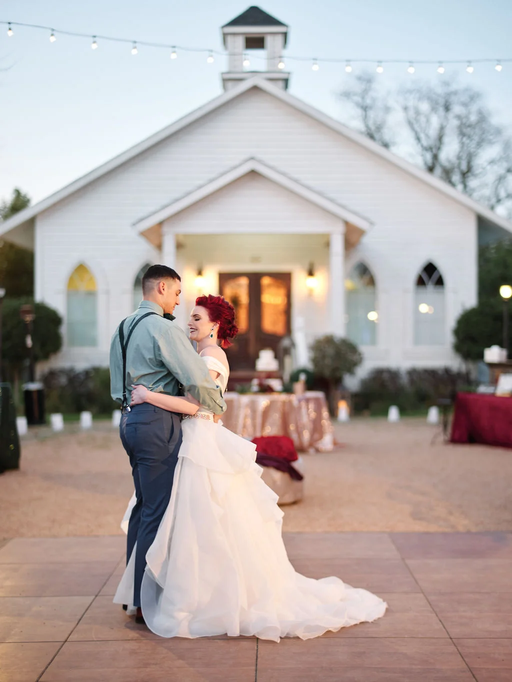 Lauren and Justin dancing in front of the white chapel at dusk